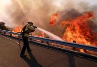 A firefighter battles a fire along the Ronald Reagan Freeway, aka state Highway 118, in Simi Valley, Calif. Photo by Ringo H.W. Chiu/AP
