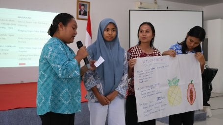 Ina (memegang mikrofon) sedang membacakan resep dan bahan-bahan makanan yang mereka dapatkan dalam sesi permainan “Dapur Tanpa Sisa”.