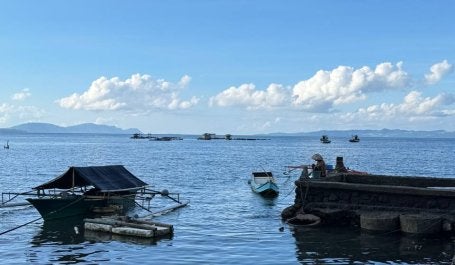 Seorang nelayan memancing di pesisir Desa Bulutui yang penuh sampah.