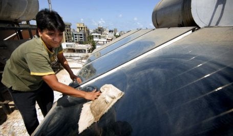 Wiping down rooftop solar panels in Mumbai. Flickr/The Climate Group