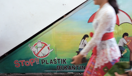 Seorang perempuan berjalan di depan mural pelarangan plastik. Kredit foto: NPAP