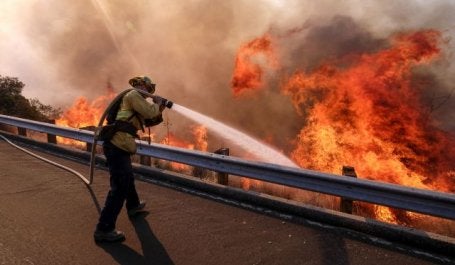 A firefighter battles a fire along the Ronald Reagan Freeway, aka state Highway 118, in Simi Valley, Calif. Photo by Ringo H.W. Chiu/AP