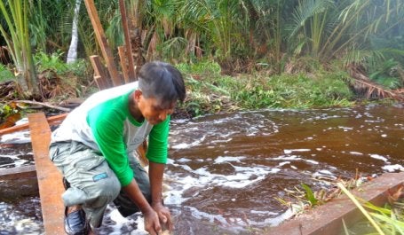 Abdul Manan, memperbaiki sekat kanal, kala Presiden Joko Widodo, datang ke Desa Sungai Tohor, Riau, akhir November 2014. Warga berupaya menahan air agar tak lepas dengan membuat sekat-sekat di kanal. Kredit foto: Indra Nugraha/ Mongabay Indonesia